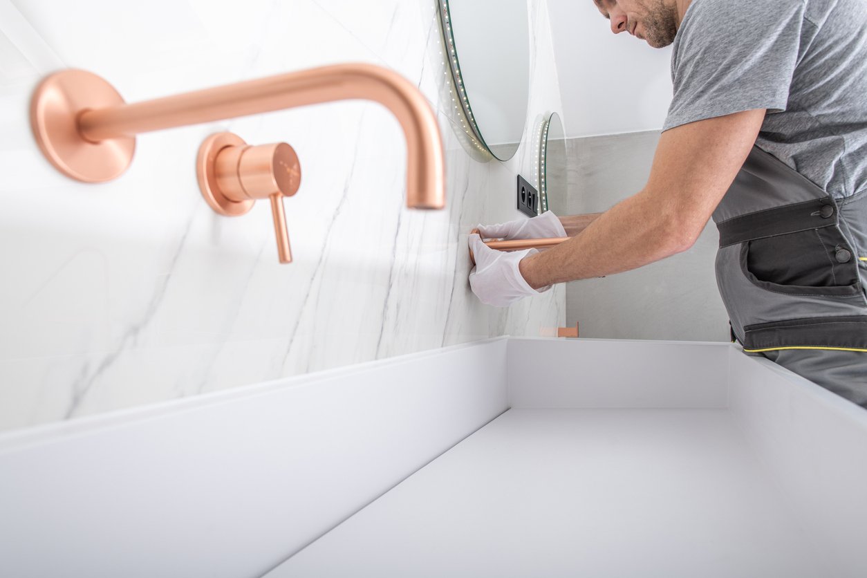 Man Installs Marble Backsplash with Copper Bathroom Faucet